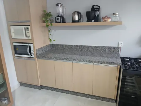 Cozinha com bancada em granito cinza e eletrodomésticos embutidos, obra em Sinop