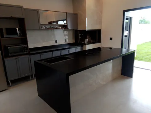 Cozinha planejada com ilha e bancada em granito preto em obra entregue em Sinop-MT